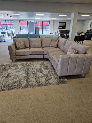 Gray sectional sofa in a showroom setting with large windows.